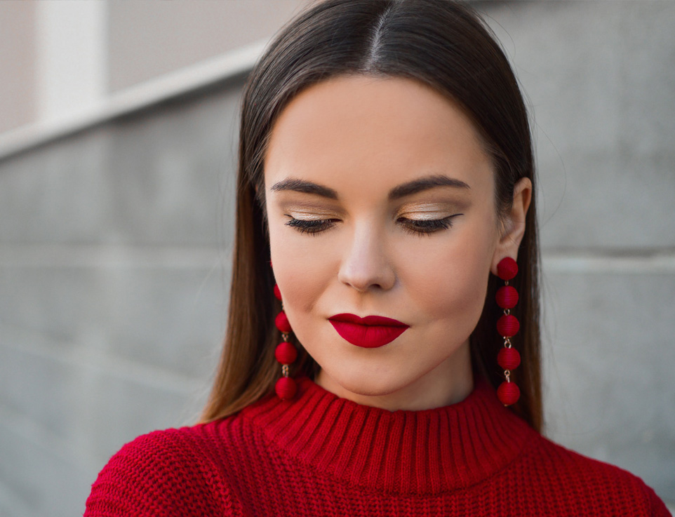 Image of a woman with red sweater and looking downwards with a smile